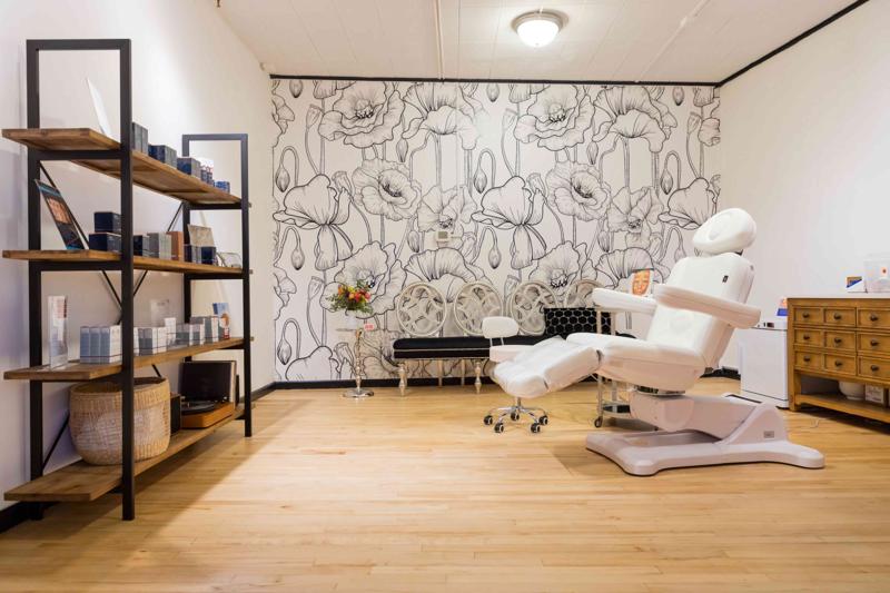 The treatment room at The Little Med Spa, with a hand-painted poppy mural and skincare display shelving